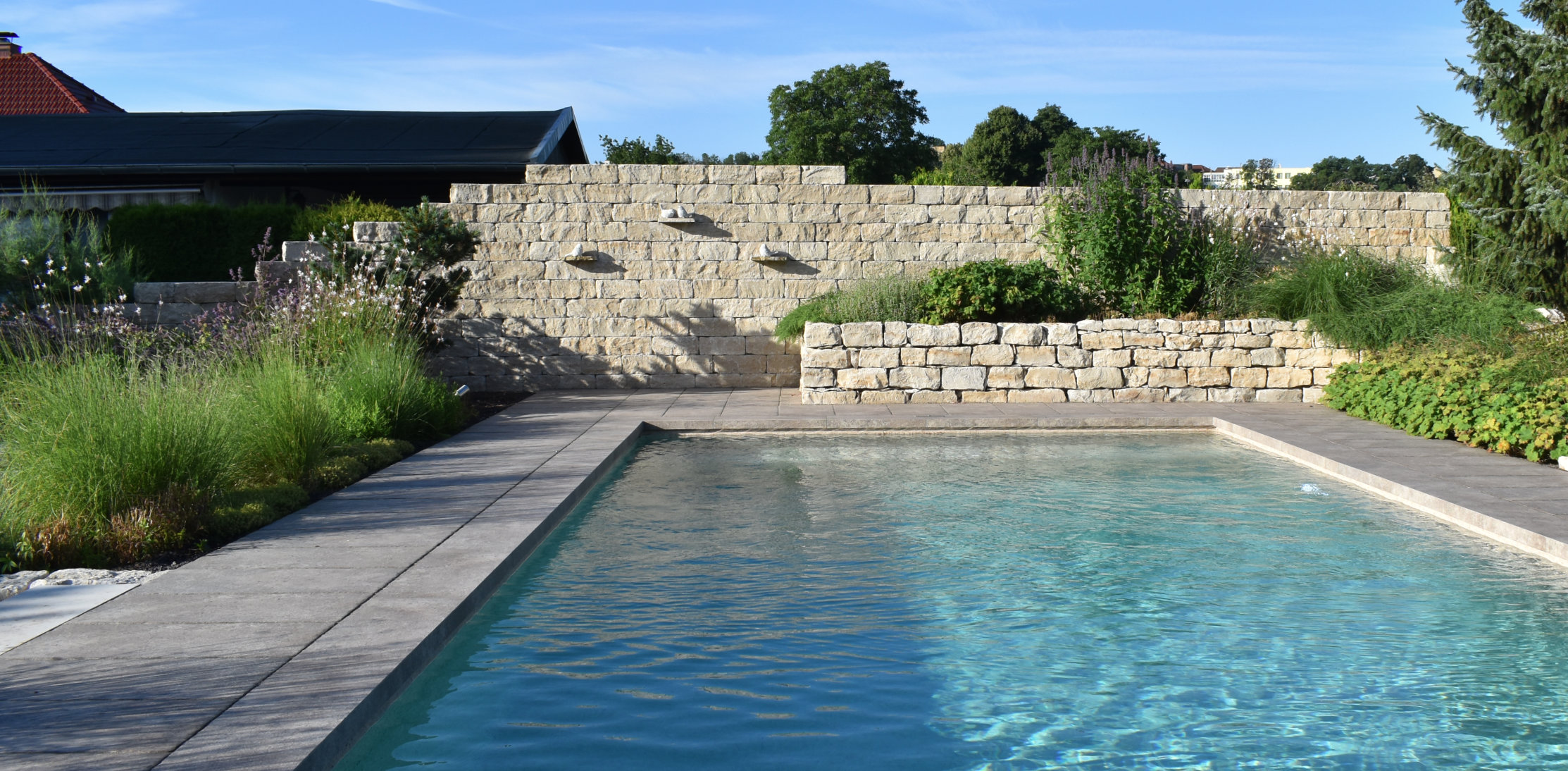 Poolgestaltung mit Garten und Natursteinmauer